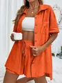 Detail of orange two-piece linen set featuring button-up shirt and elastic waist shorts - S / Top And Bottom / Orange Red