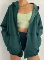 Close-up of a women's dark green oversized zip-up hoodie with front pockets detail - S / Tops / Dark Green