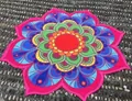 Vue détaillée d'une serviette de plage mandala colorée sur un sol de galets gris. - Mandala Lotus