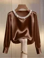 Close-up of elegant satin blouse with pearl-embellished neckline and smooth texture - Dark Brown