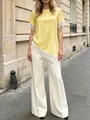Primo piano di una t-shirt in raso giallo con bordo in pizzo bianco e orlo asimmetrico - Taglia S / Top / Giallo
