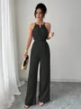 Full-body view of a black halter-neck jumpsuit with a cinched waist and elegant wide legs. - S / Black