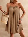Détail d'une mini-robe dos nu marron en tissu froissé avec un sac en paille chic - Café Clair