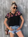 Detailed view of the vibrant embroidery and tassel necktie on the black boho blouse. - S / Tops / Black
