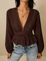 Detailed shot of a brown deep V-neck blouse featuring delicate lace trim and ruffle hem. - Coffee