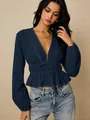 Elegante marineblauwe peplum blouse met diepe V-hals, strikceintuur en verfijnd kantdetail. - Marineblauw