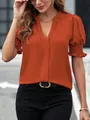 Primo piano di un'elegante camicetta arancione con scollo a V e maniche a sbuffo alla moda - Arancione