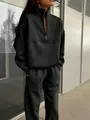 Detail of a chic black two-piece tracksuit set with a half-zip pullover and joggers - Black