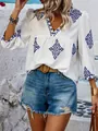 Nahaufnahme einer eleganten weißen Damenbluse mit blauer Boho-Stickerei und V-Ausschnitt - S / Oberteile / Weiß mit blauen Blumen