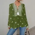 Close-up detail of green bohemian blouse featuring white embroidery and tassel neck tie - S / Tops / Green