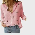 Detailed view of pink linen shirt featuring black bird prints and casual buttons - S / Tops / Printed Pink