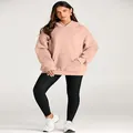 Full body view of a woman wearing an oversized nude pink hoodie with black leggings - Lotus Pink