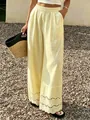 Gros plan de l'ourlet en dentelle élégante sur le pantalon large en coton et lin jaune - S / Bas / Jaune