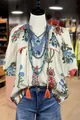 Blusa bohemia con estampado floral, cuello en V y borlas naranjas en un maniquí - S / Tops / Blanco Roto