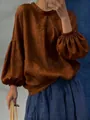 Détail de cette blouse ample en lin marron avec élégantes manches lanternes et col rond. - Châtain
