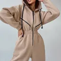 Nahaufnahme eines beigen Damen-Kapuzen-Overalls mit dekorativen Brust-Reißverschlüssen. - Aprikose