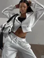 Close-up detail of women's white two-piece tracksuit with zip-up jacket and sweatpants - S / Top And Bottom / White
