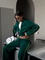 Detail shot of woman wearing dark green zip-up tracksuit with white piping - S / Top And Bottom / Green