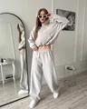 Full view of a stylish woman in a gray two-piece tracksuit in a modern interior mirror room. - S / Top And Bottom / Gray