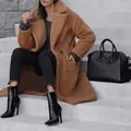 Detailed view of a brown teddy coat with double-breasted buttons in an urban setting. - XS / Tops / Khaki