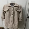 Detailopname van een beige pluchen jas met een gezellige omslagkraag en donkere knopen. - S / Tops / Abrikoos
