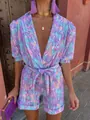 Detailed view of dopamine style deep V-neck puff sleeve romper with vibrant floral print. - S / Jumpsuits / Purple