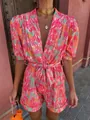 Detail shot of vibrant dopamine print romper with deep V-neck and puff sleeves - S / Jumpsuits / Red