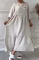 Detail view of a beige linen-style maxi dress featuring a round neck and elegant flower brooch - Beige