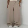 Detailansicht der beigen Hose mit hohem Bund, weitem Bein und versetztem Knopfdesign - Aprikose