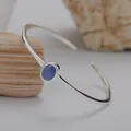 Detailaufnahme eines S925 Silberarmreifs mit einem blauen Edelstein auf Naturstein - Natürlicher Kyanit Armreif / Blau