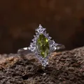 Primer plano de un anillo de peridoto verde talla marquesa con racimo de topacios blancos - Anillo de Peridoto / Verde oliva