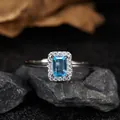Detailed macro shot of an emerald-cut blue topaz silver ring on dark stones. - Natural Topaz Ring / Silver