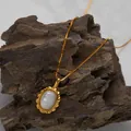 Close-up detail of a gold necklace with an oval white shell pendant on natural rock - Natural White Shell Necklace / Gold