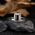 Close-up of a rectangle garnet ring with clear stone halo setting on a dark rock base - Natural Garnet Ring / Silver