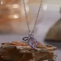 Detailopname van een paarse amethist strikhanger aan een zilveren ketting. - Strik Ketting (R393) / 40+5cm Kettinglengte / Paars (Natuurlijke Amethist)