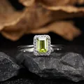 Close-up detail of an elegant emerald cut peridot silver ring with halo stones on rocks - Natural Peridot Ring / Silver