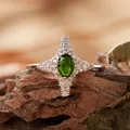 Dettaglio macro di un anello a stella in argento con gemma verde su legno naturale - Stile Stella a Quattro Punte (R421) / Diopside Naturale