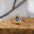 Nahaufnahme eines Vintage-Rings mit blauem Saphir-Halo auf strukturiertem Stein - Natürlicher Saphirring / Gold