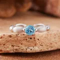 Close-up of s925 silver ring with a round blue topaz gemstone on a textured rock - Natural Topaz Ring