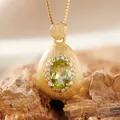 Close-up of a luxury brushed gold teardrop pendant featuring an oval green gemstone. - Natural Peridot Necklace Gold / Necklace