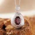 Close-up of a brushed S925 silver pendant featuring an oval-cut red garnet gemstone. - Natural Garnet Necklace Silver / Necklace
