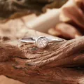 Macro shot of a S925 silver ring with a round clear gemstone on a natural wood branch. - Open Ring / Moissanite Ring
