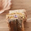 Close-up of gold bamboo link bracelet with oval purple tanzanite and leaf charm - Natural Tanzanite Bracelet