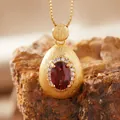 Close-up of teardrop brushed gold pendant with oval red garnet and white zircon accents. - Natural Garnet Necklace Gold