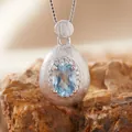 Macro view of brushed S925 silver teardrop pendant with light blue gemstone and small crystals - Natural Topaz Necklace Silver