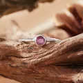 Close-up of a S925 silver ring featuring a round pink gemstone on a rustic wood surface. - Open Ring / Natural Ruby
