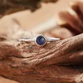 Detailed macro shot of a S925 silver ring with a round blue sapphire on a wood texture - Open Ring / Natural Blue Sapphire