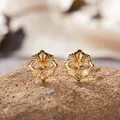 Nahaufnahme von goldenen Vintage-Ohrringen mit hohlem Blumenmuster und gelbem Edelstein im Fokus - Natürlicher Citrin Ohrstecker (LS163) / Gold