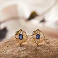 Nahaufnahme goldener Ohrringe im Vintage-Blumendesign mit blauen Edelsteinen auf Steinoberfläche - Natürlicher Saphir Ohrstecker (LS163) / Gold