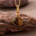 Detailed close-up showing the natural chatoyancy of a round tiger's eye stone pendant. - Natural Tiger's Eye Style (N470) / Gold